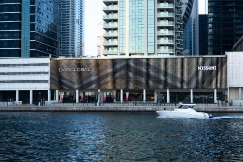 a white boat in the water in front of a building at Lusso Hometels Missoni Business Bay in Dubai