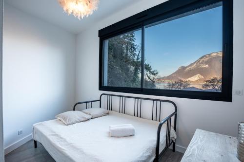 une chambre avec un lit avec une grande fenêtre dans l'établissement La Verrière du Lac, à Sévrier