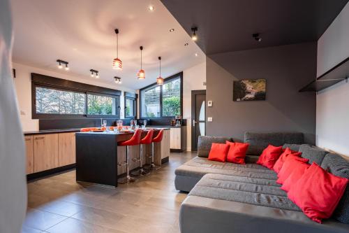 - un salon avec un canapé et un bar avec des oreillers rouges dans l'établissement La Verrière du Lac, à Sévrier