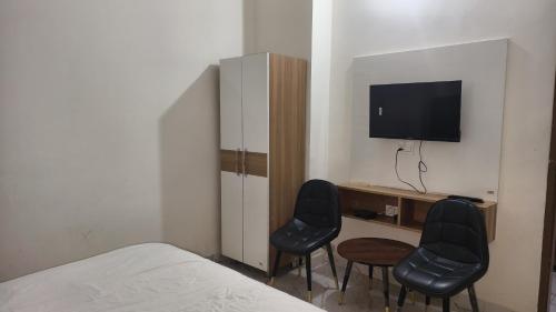 1 dormitorio con 2 sillas y escritorio con TV en Hotel Sundram, en Zirakpur