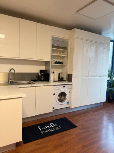 une cuisine avec des armoires blanches et une machine à laver dans l'établissement SPACIEUX Appartement de Charme, près de Paris, à Mantes-la-Jolie