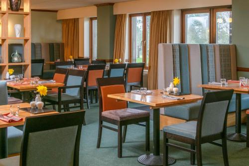 a dining room with tables and chairs and windows at Garstang Country Hotel & Golf, Sure Hotel Collection in Garstang