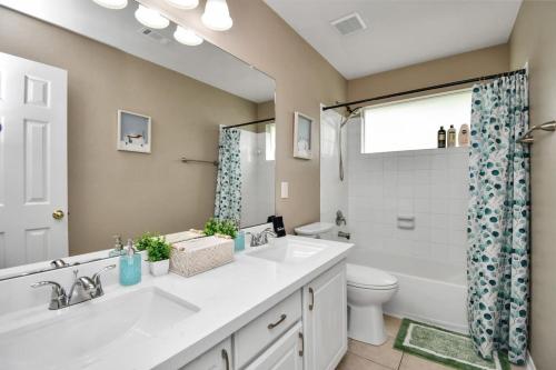 a bathroom with two sinks and a toilet and a window at The Woodlands Escape with Heated Pool and GameRoom in Conroe