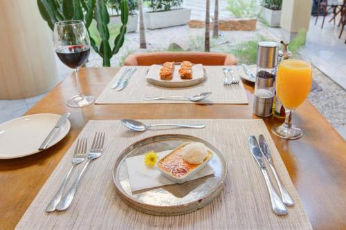 a wooden table with a plate of food and glasses of wine at Mercure Rio de Janeiro Barra da Tijuca in Rio de Janeiro