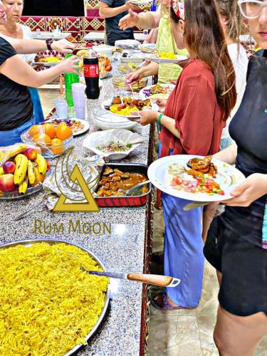 Un grupo de personas de pie alrededor de una mesa con comida. en Rum Moon Bubbles Luxury Camp, en Wadi Rum