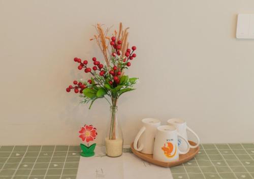 a vase with flowers and cups on a counter at The Sóng Vũng Tàu- SAO VIỆT Căn Hộ Nghỉ Dưỡng 5 Sao in Vung Tau
