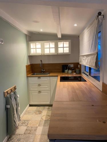 une cuisine avec des armoires blanches et un plancher en bois dans l'établissement Hameau au coeur de la foret landaise, à Herm