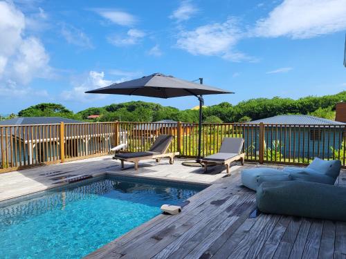 a patio with a pool and an umbrella and chairs at SALTY LODGE Villa 3 chambres piscine "ALIZES" - Pointe Faula in Le Vauclin