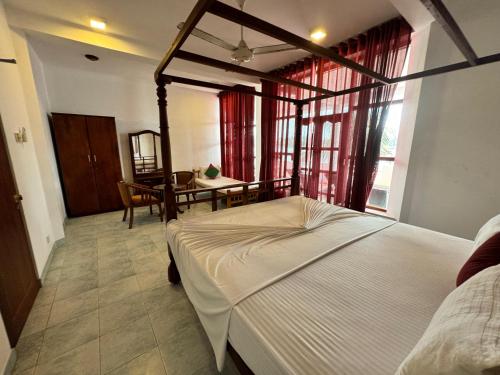a bedroom with a bed and a dining room with a table at Luthmin River View Hotel in Alutgama