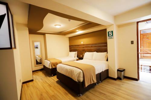 una camera d'albergo con due letti e una finestra di INKALAM cusco a Cuzco