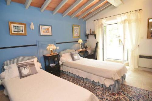 Cette chambre bleue comprend 2 lits et une fenêtre. dans l'établissement Prestige property with pool in the Alpilles, à Orgon