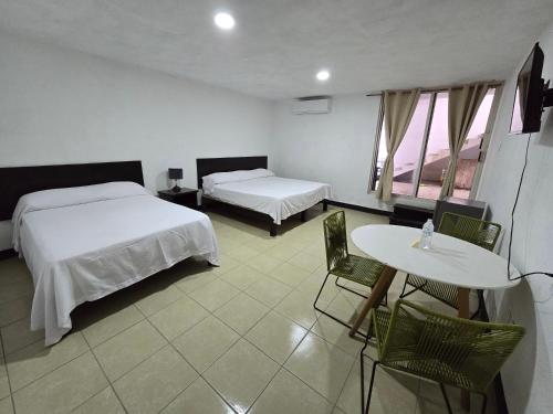 a hotel room with two beds and a table and chairs at Hotel Villa Capricho in Ciudad Madero