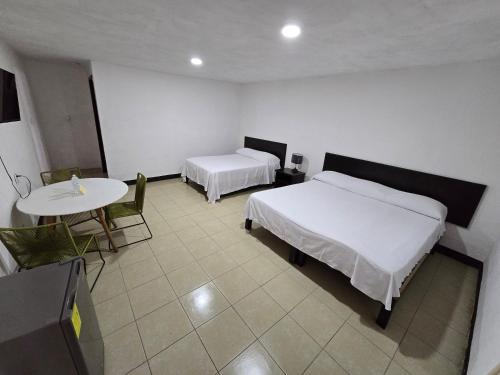a hotel room with two beds and a table and a table and a tableastery at Hotel Villa Capricho in Ciudad Madero