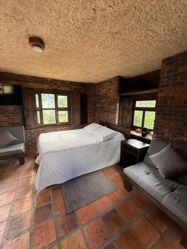 a bedroom with a large bed and a couch at El Agrado Restaurante Cabañas in Líbano