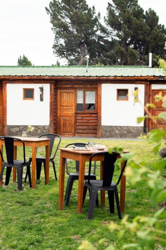 un tavolo da picnic con sedie di fronte a una cabina di Oliva Hostería y Apart a El Calafate