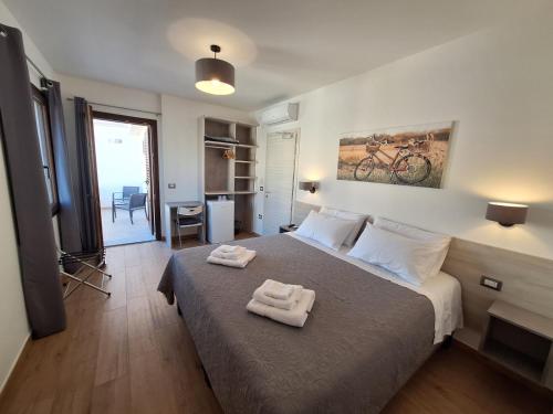 a bedroom with a bed with two towels on it at COMIDA Guesthouse & Experiences in Tortolì