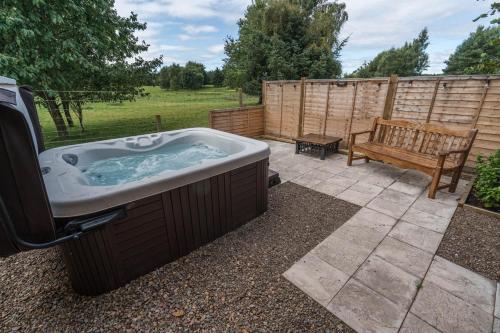 a hot tub in a yard with a bench at Whitemoss Lodge in Dunning