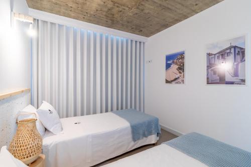 a bedroom with two beds and a window at Refúgio com Spa e Vista Mar - Ribamar Bluevillas in Ribamar