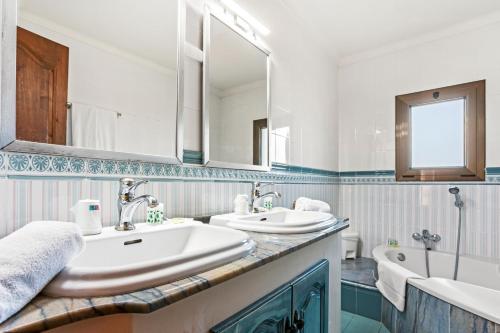 une salle de bain avec deux lavabos, une baignoire et un miroir dans l'établissement 28 Maria Levy's, à Saint-Tropez