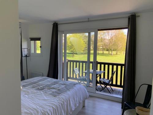une chambre avec un lit et un balcon avec une table dans l'établissement Manoirs du Golf domaine privé 3 chambres, à Tourgéville