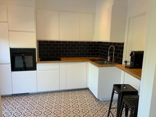 La cuisine est équipée de placards blancs et d'un four micro-ondes noir. dans l'établissement Manoirs du Golf domaine privé 3 chambres, à Tourgéville