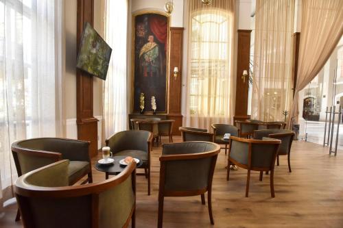 a waiting room with chairs and tables and a painting at Plaza Camelinas Hotel in Querétaro