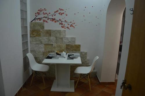 卡尔塔吉罗Modern Apartment in Caltagirone, 40 m² with Balcony的一张带椅子的白色桌子和墙上的一棵树