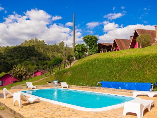 einen Pool mit Stühlen und einem Hügel in der Unterkunft Pousada Natureza da Terra in Monte Verde