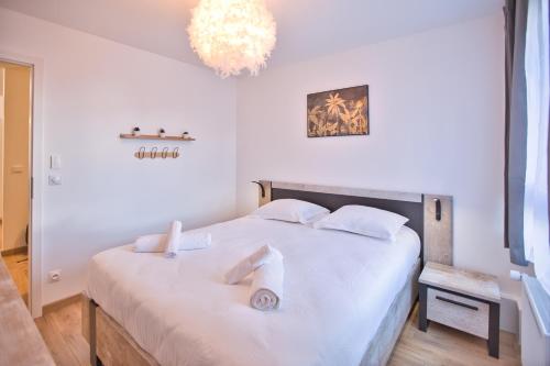 - une chambre avec un lit blanc et un lustre dans l'établissement Appartement baignoire balnéo, à Annecy
