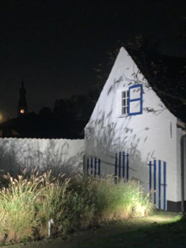 a small white building with a clock tower in the background at Hamiora wellness B&B in Deinze