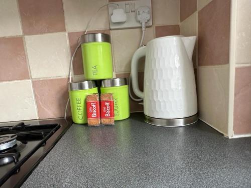 a kitchen counter with three cups and a coffee maker at Homely Milton Keynes Stay! in Milton Keynes