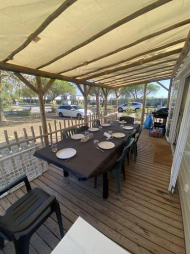 une terrasse en bois avec une grande table et des chaises dans l'établissement Lac Des Reves Monparadis 58, à Lattes