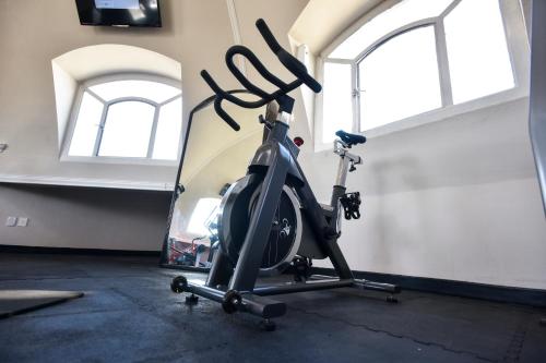 a gym with a exercise bike in a room with windows at Plaza Camelinas Hotel in Querétaro