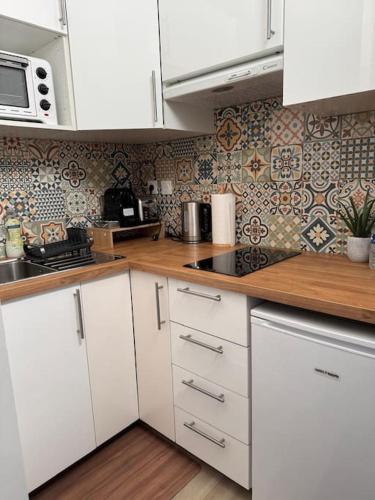 une cuisine avec des armoires blanches et un comptoir en bois dans l'établissement studio portes de paris - Arago, à Saint-Ouen