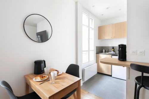 - une cuisine et une salle à manger avec une table et un miroir dans l'établissement GuestReady - Cozy Parisian Escape for 2, à Paris
