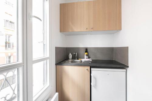 une cuisine avec un évier et une fenêtre dans l'établissement GuestReady - Cozy Parisian Escape for 2, à Paris