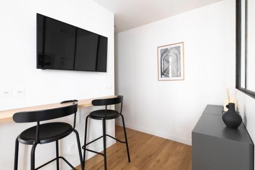 Cette chambre dispose de deux tabourets de bar et d'une télévision à écran plat. dans l'établissement GuestReady - Cozy Parisian Escape for 2, à Paris