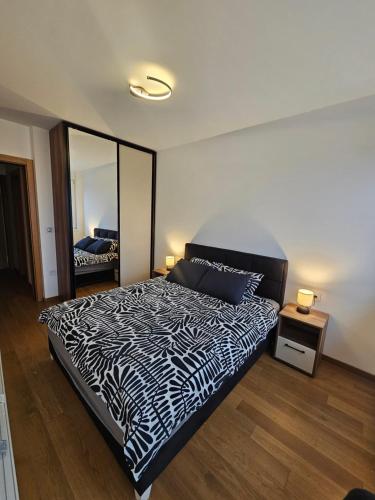 a bedroom with a black and white bed and a mirror at Skyline Cozy Suites in Novi Sad