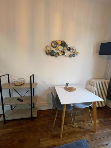 une table et des chaises dans une pièce avec une plaque murale dans l'établissement Opale 1, à Vichy