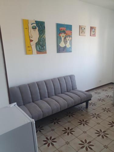 a couch in a room with paintings on the wall at Dc apartment in Santa Maria Capua Vetere