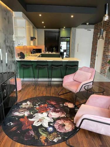 a living room with pink chairs and a rug at Sky Loft - Modern Oasis in the heart of the city in Cape Town