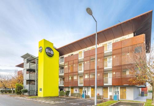 a building with a yellow column next to a street light at B&B HOTEL Saint-Malo Centre in Saint Malo