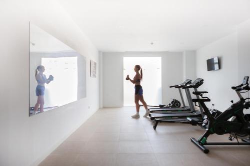 a woman walking in a gym with a mirror at Ibersol Siurell in Sa Coma