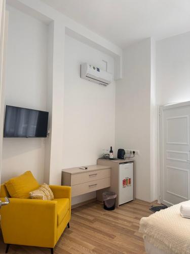 a living room with a yellow couch and a tv at Joanna's Rooms in Kalopanayiotis