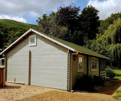 a small white and green building with at Cosy Log Cabin in Llanfoist village in Abergavenny