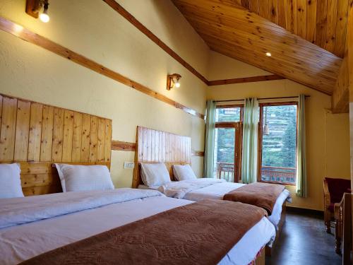 two beds in a room with wooden walls and wooden ceilings at Crystal Mountain Jibhi in Jibhi