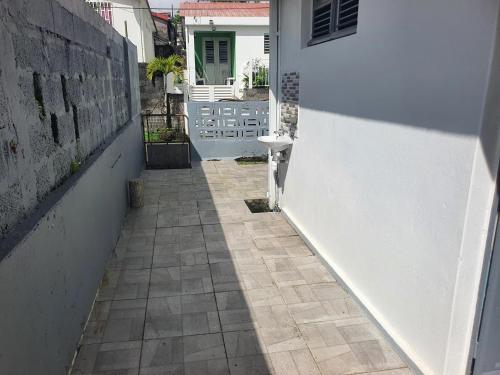 an alley way with a white wall and a door at Maison agréable avec terrasse à Le Morne Rouge in Le Morne Rouge