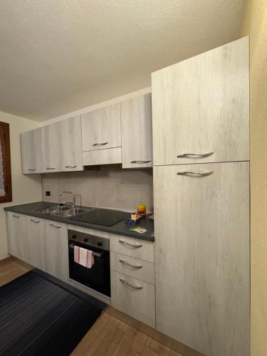 a kitchen with white cabinets and a sink at Orobie Holiday Apartments in Albosaggia