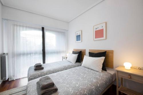 a bedroom with two beds and a window at Apartamento agradable con parking en Gros in Donostia-San Sebastián