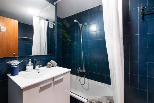 a bathroom with a sink and a shower with blue tiles at Apartamento agradable con parking en Gros in Donostia-San Sebastián